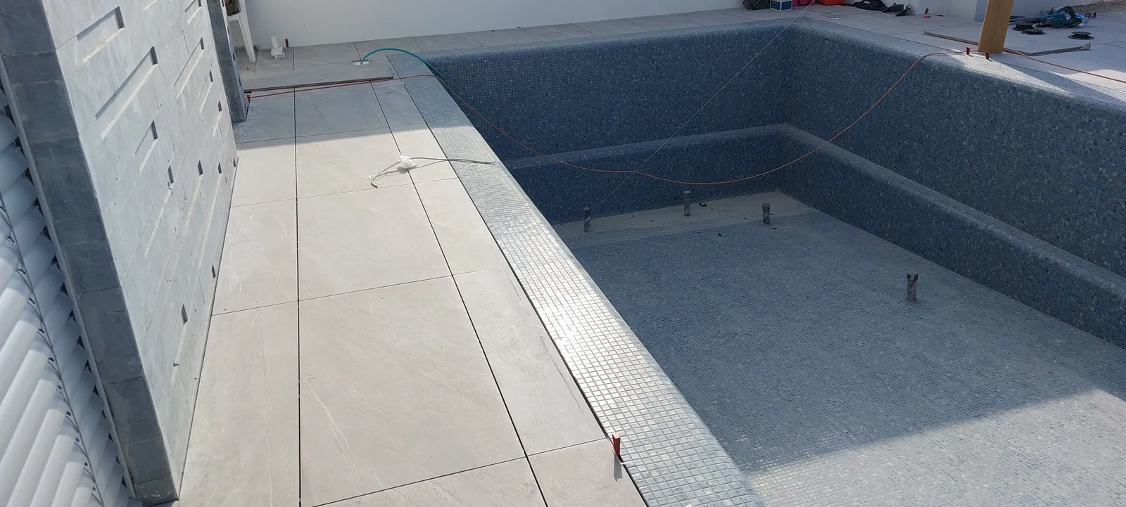 Pool deck in large porcelain pavers around a new pool.