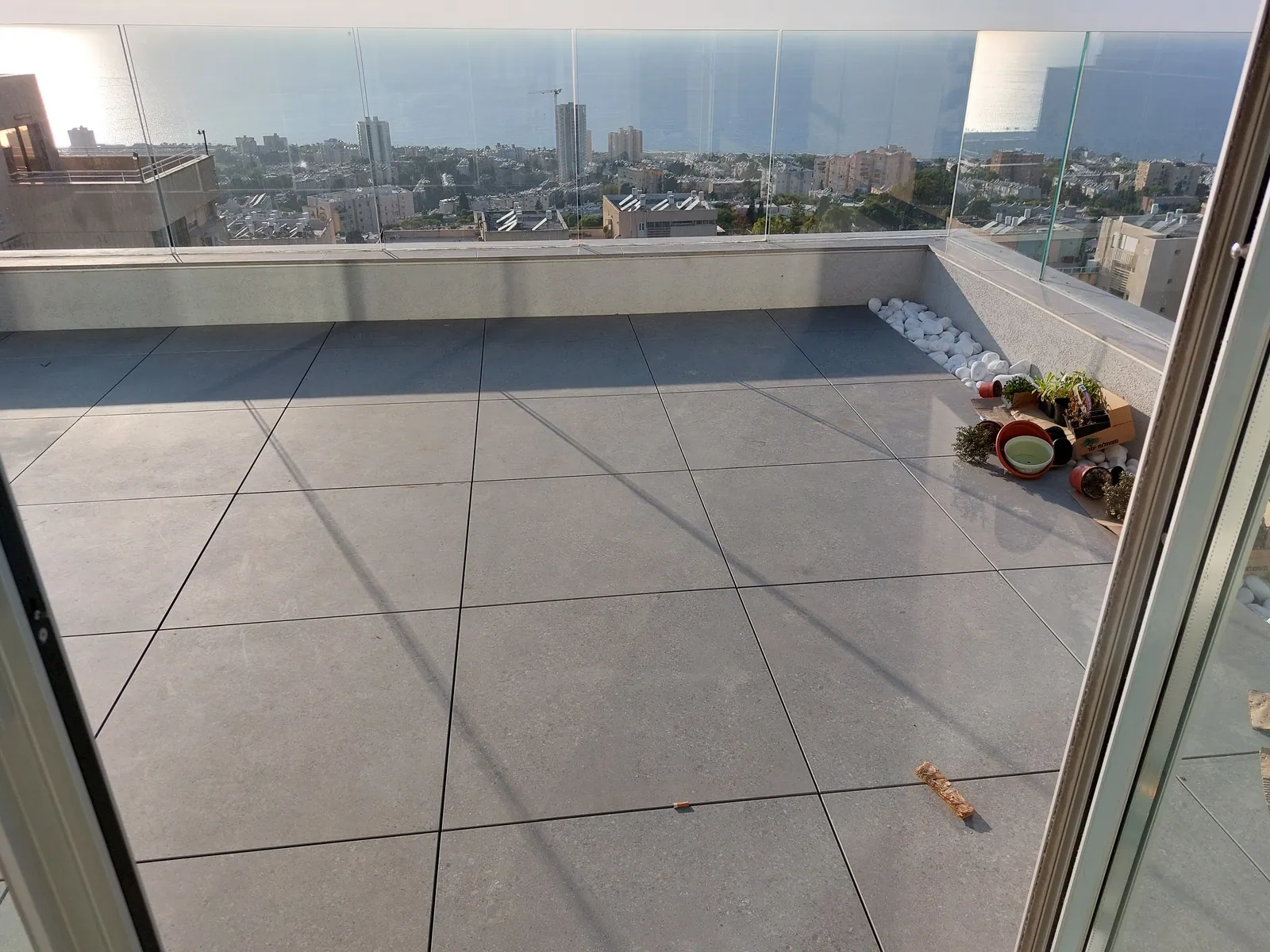 Finished rooftop terrace with porcelain pavers and glass railing.